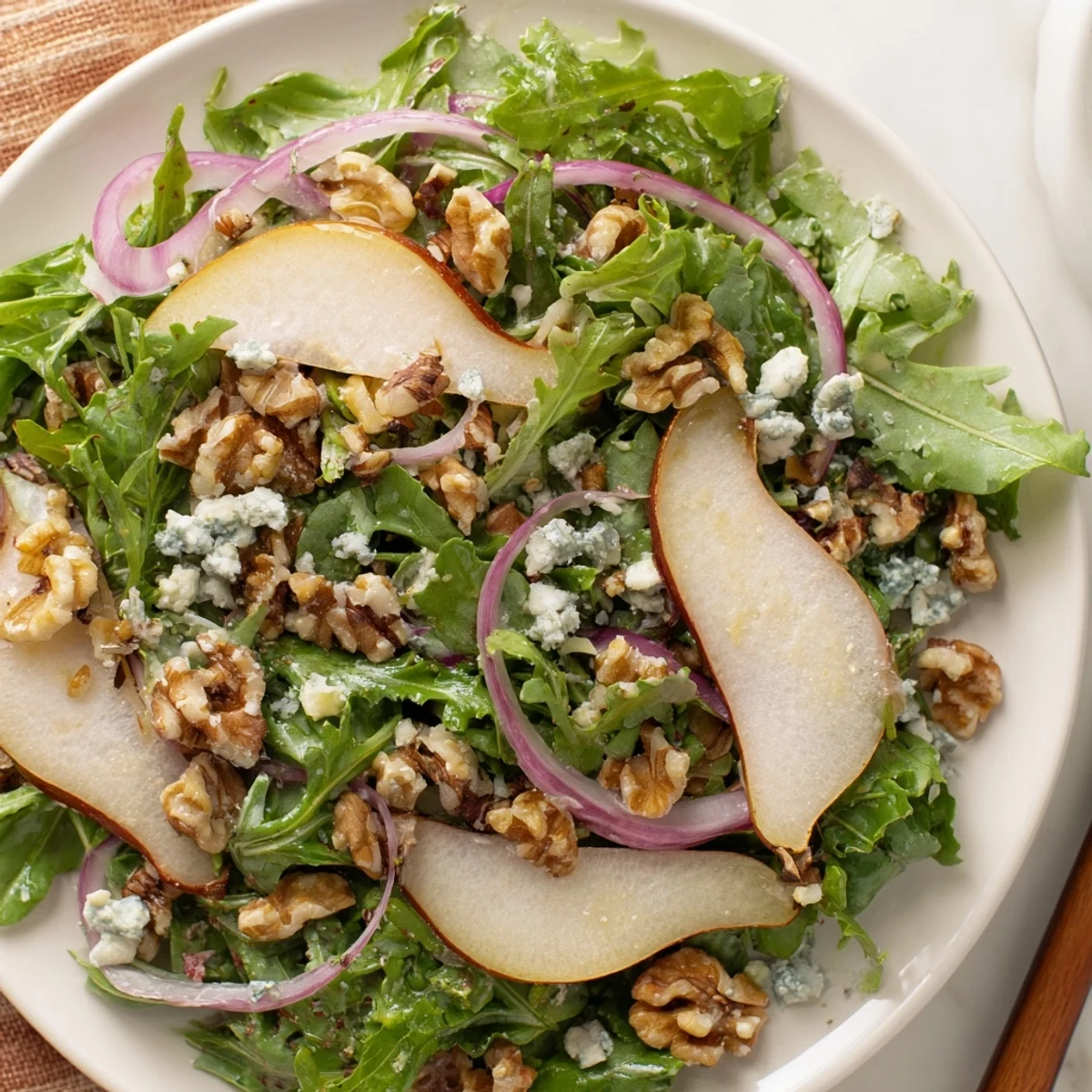 Fresh winter green salad with pear and walnuts, tossed with a tangy vinaigrette, ready to serve.