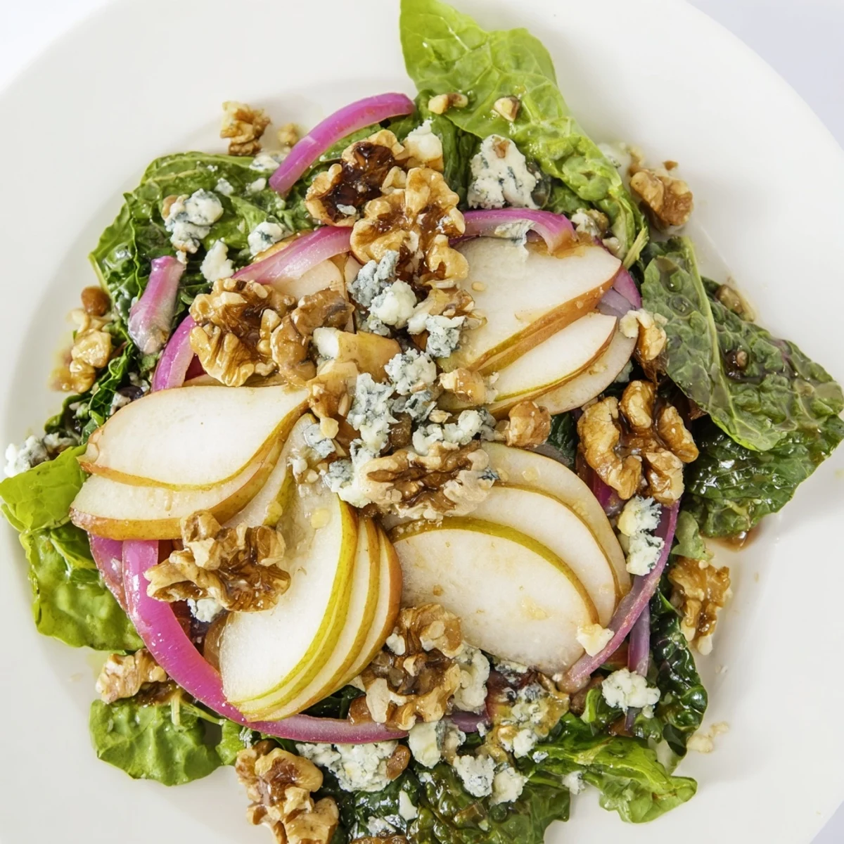 A beautiful close-up of the finished winter green salad with pear and walnuts; colors are vibrant.