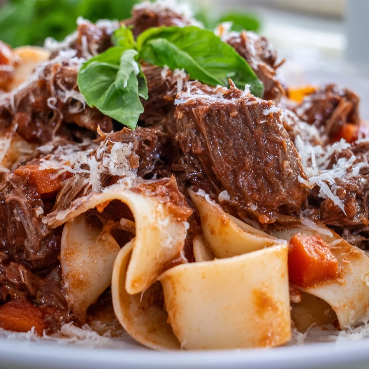 Tender slow cooker beef ragu with pappardelle pasta, topped with fresh basil and grated Parmesan for a cozy family meal.