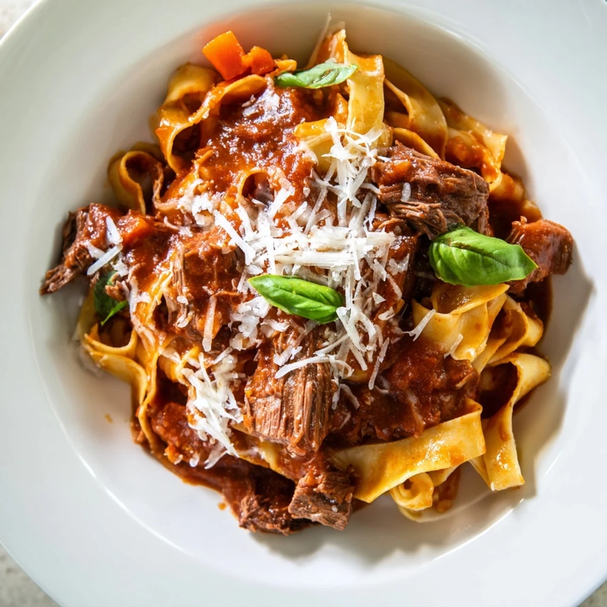 Fork-tender Slow Cooker Beef Ragu with Pappardelle Pasta in a rich tomato sauce, served steaming in a rustic ceramic bowl.