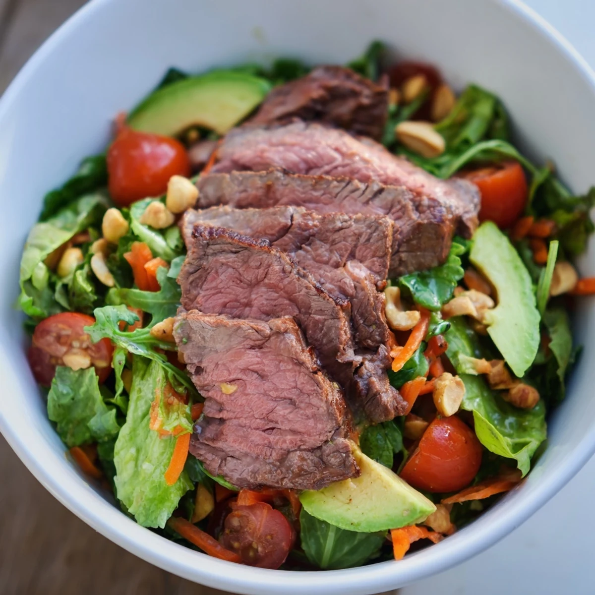 Vibrant Beef Salad Bowl with tender seared steak slices, crisp romaine, and juicy cherry tomatoes topped with fresh herbs.