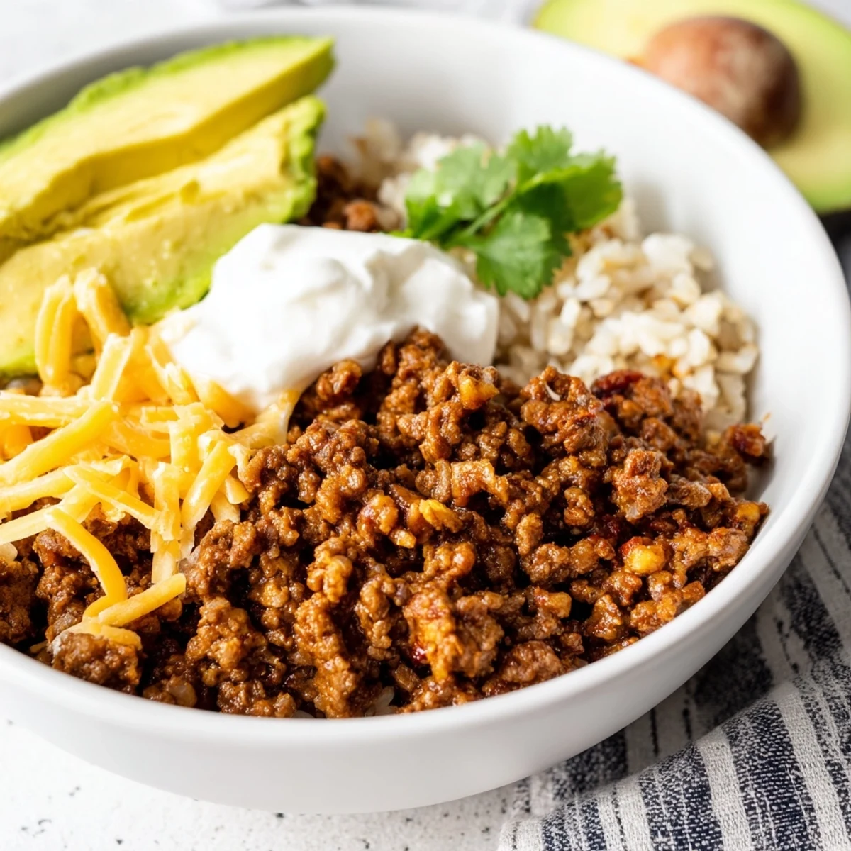 A close-up of a freshly assembled Beef Burrito Bowl with seasoned ground beef, rice, and vibrant toppings.