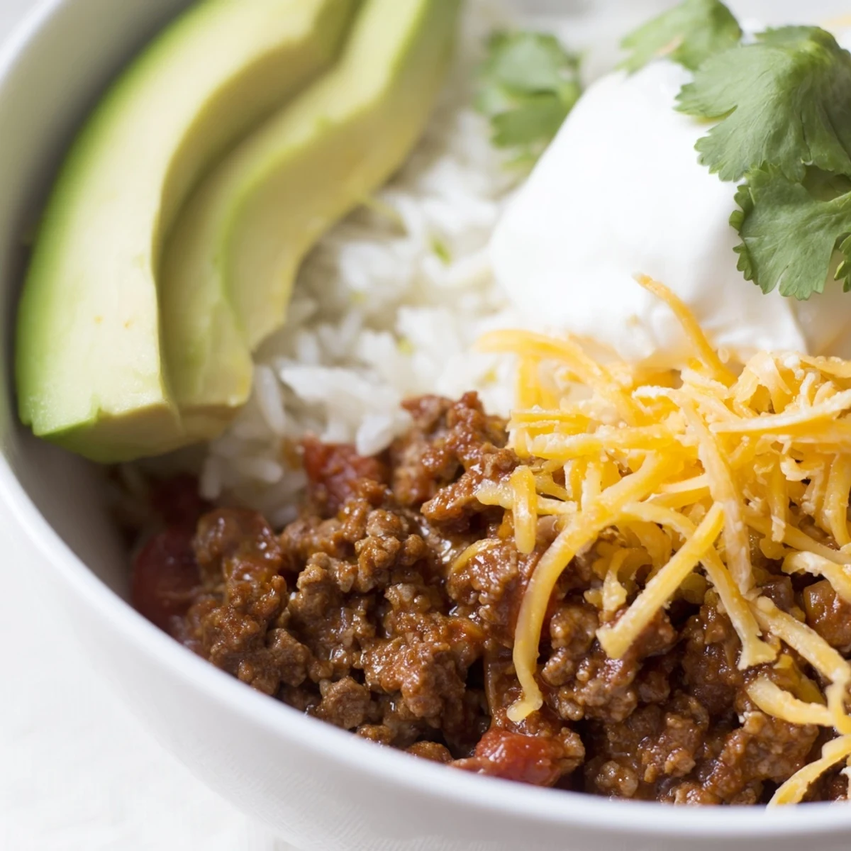 Close-up of a hearty Beef Burrito Bowl featuring tender beef, beans, and cheese with lime wedges on the side.