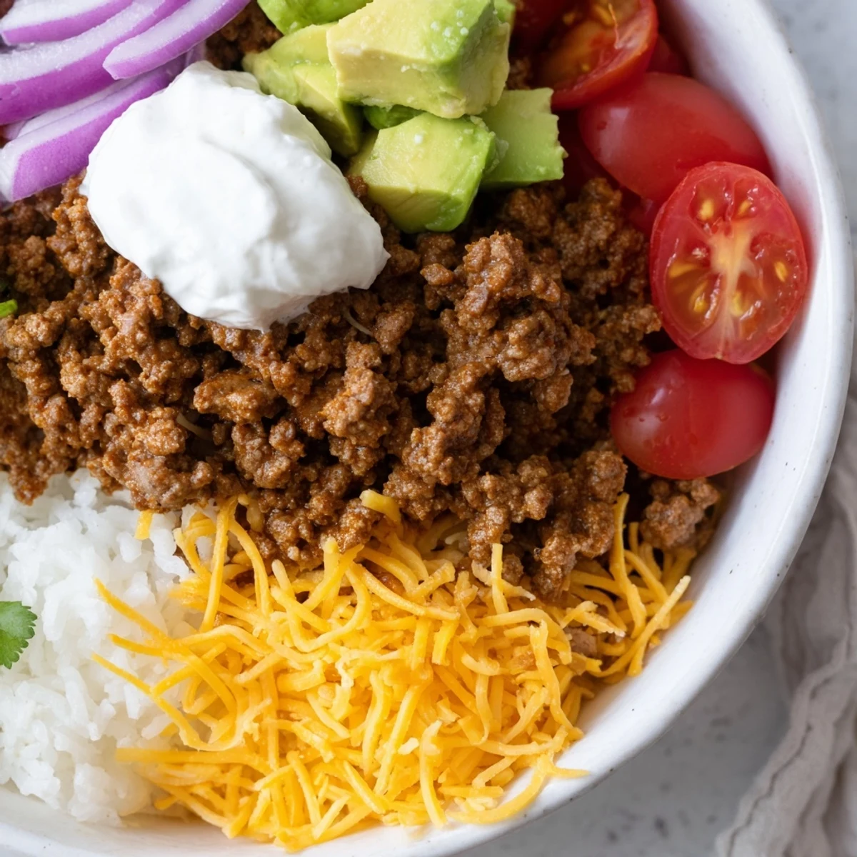 Delicious homemade beef burrito bowls featuring seasoned meat, zesty cilantro rice, black beans, and colorful fresh toppings for a quick dinner.