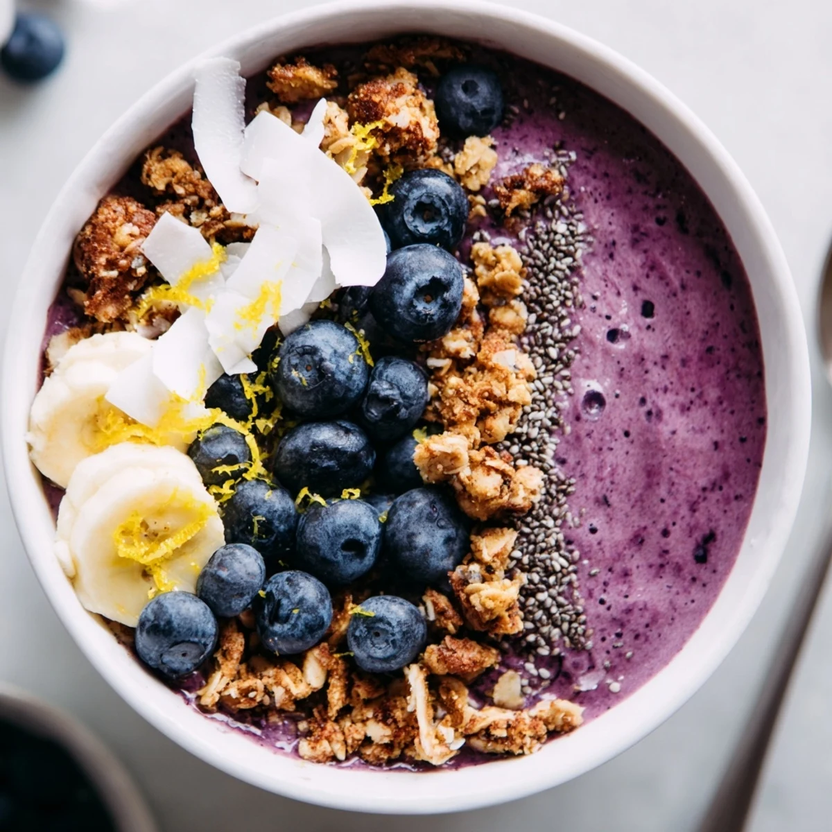 Refreshing Lemon Blueberry Smoothie Bowl topped with granola and lemon zest, ready to enjoy with a spoon.