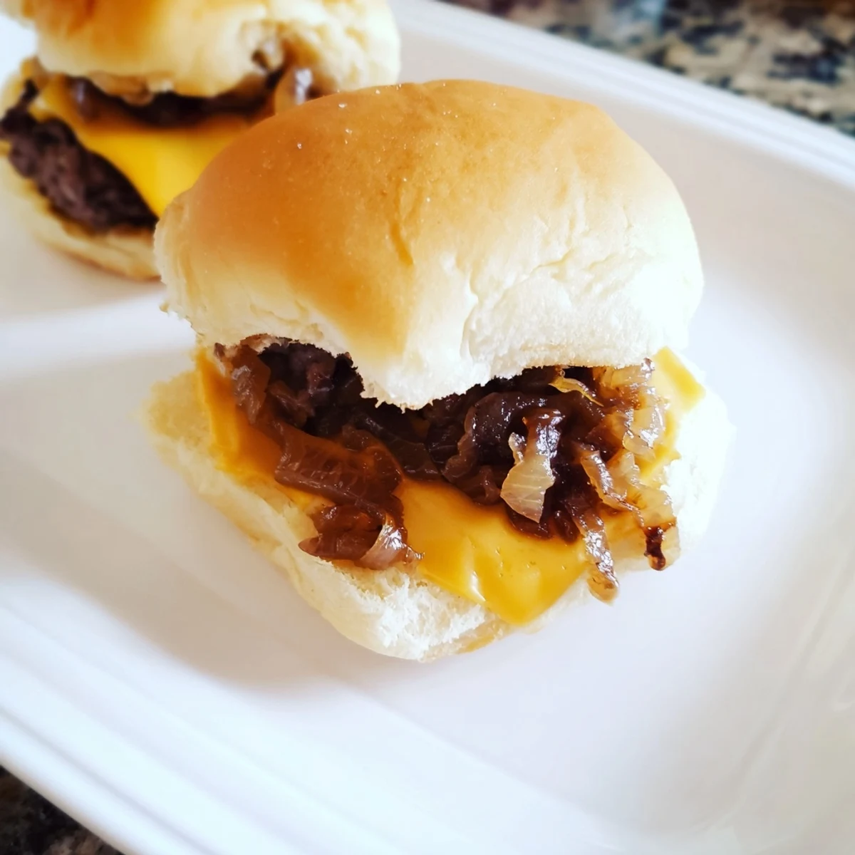Juicy mini beef sliders topped with golden caramelized onions on soft buns, ideal for a hearty party snack.  