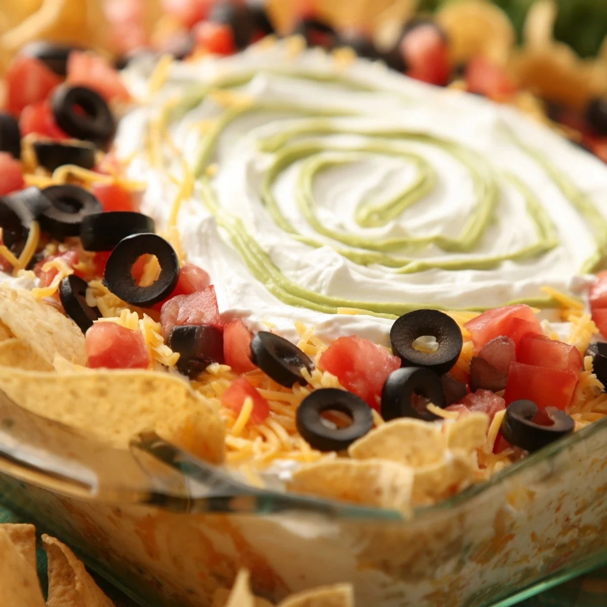 Freshly prepared Super Bowl Seven Layer Taco Dip served with crispy tortilla chips, garnished with black olives and green onions.  