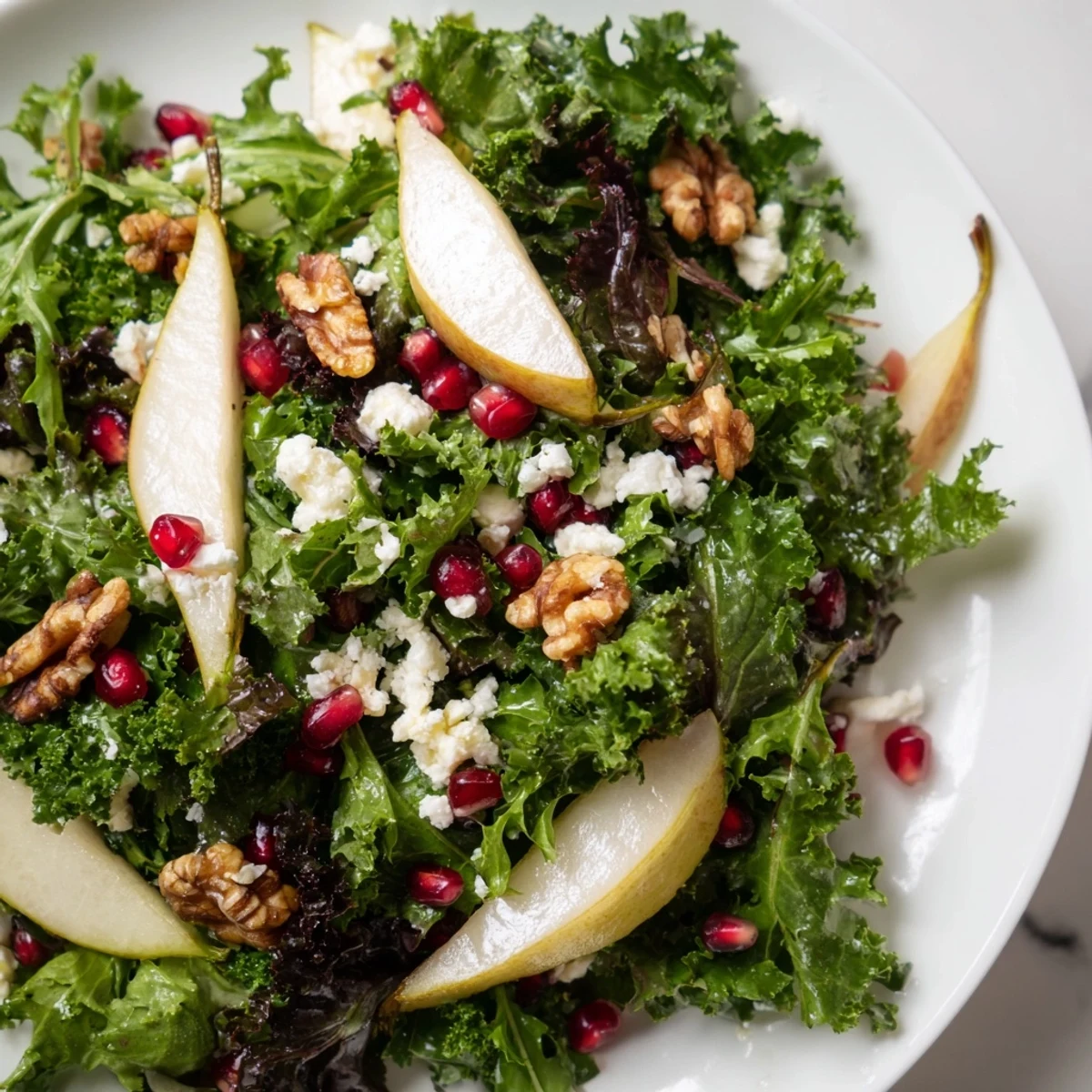 A beautiful bowl of Winter Green Salad with Pear and Walnuts featuring colorful winter greens, ripe fruit, and nuts, perfect for a healthy meal.