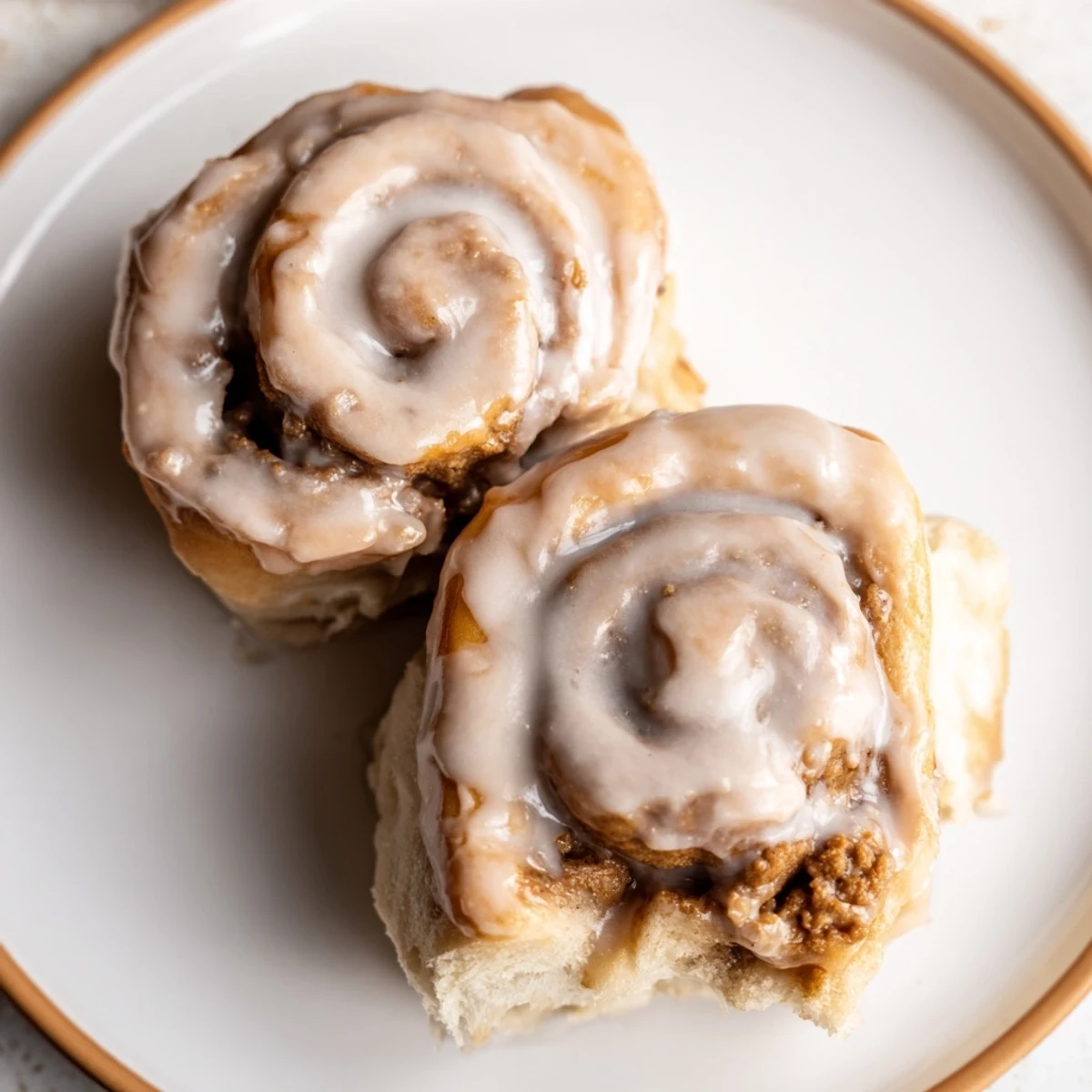 Freshly baked Soft and Gooey Biscoff Cinnamon Rolls with warm cookie butter glaze on a rustic plate.  