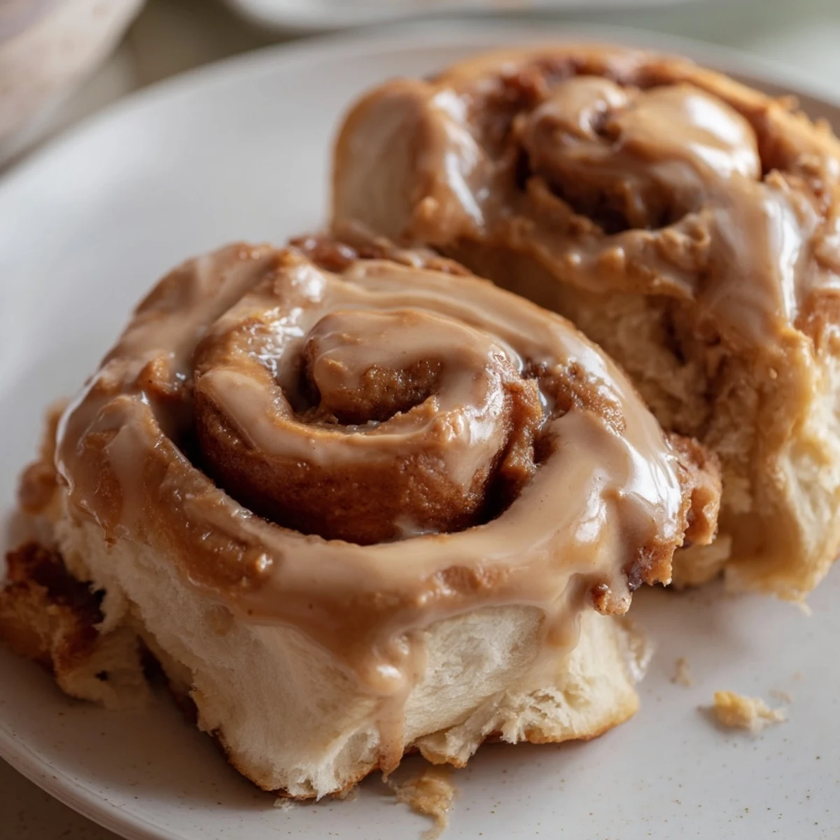 Stack of fluffy cinnamon rolls drizzled with Biscoff spread, served with a hot cup of coffee.  