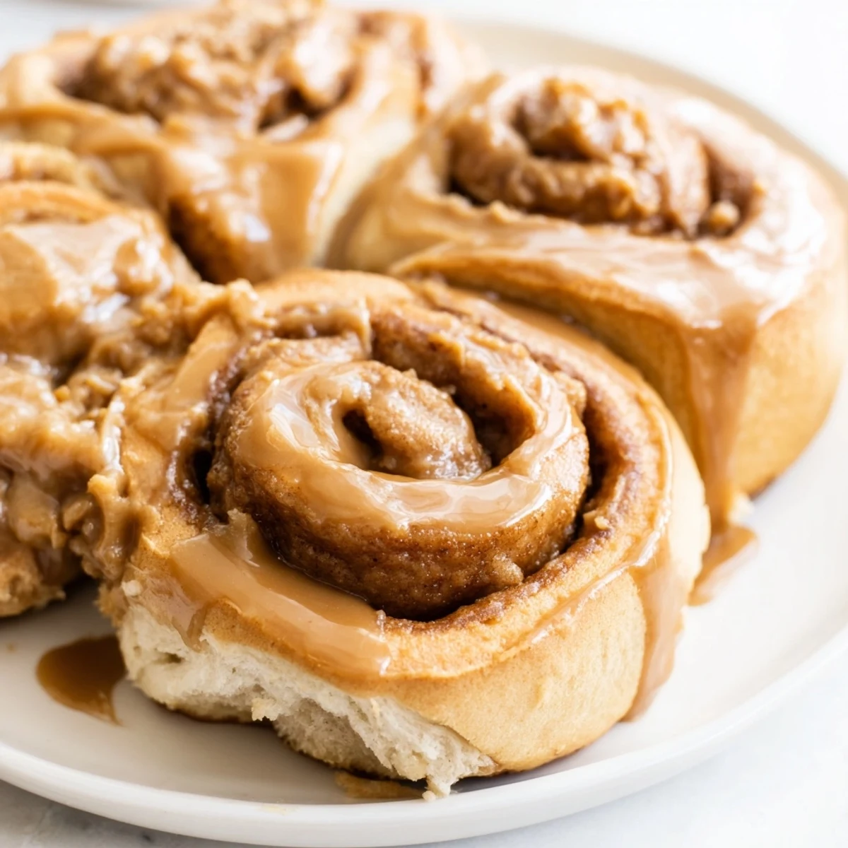 Homemade Soft and Gooey Biscoff Cinnamon Rolls with caramelized edges on a wooden cutting board.