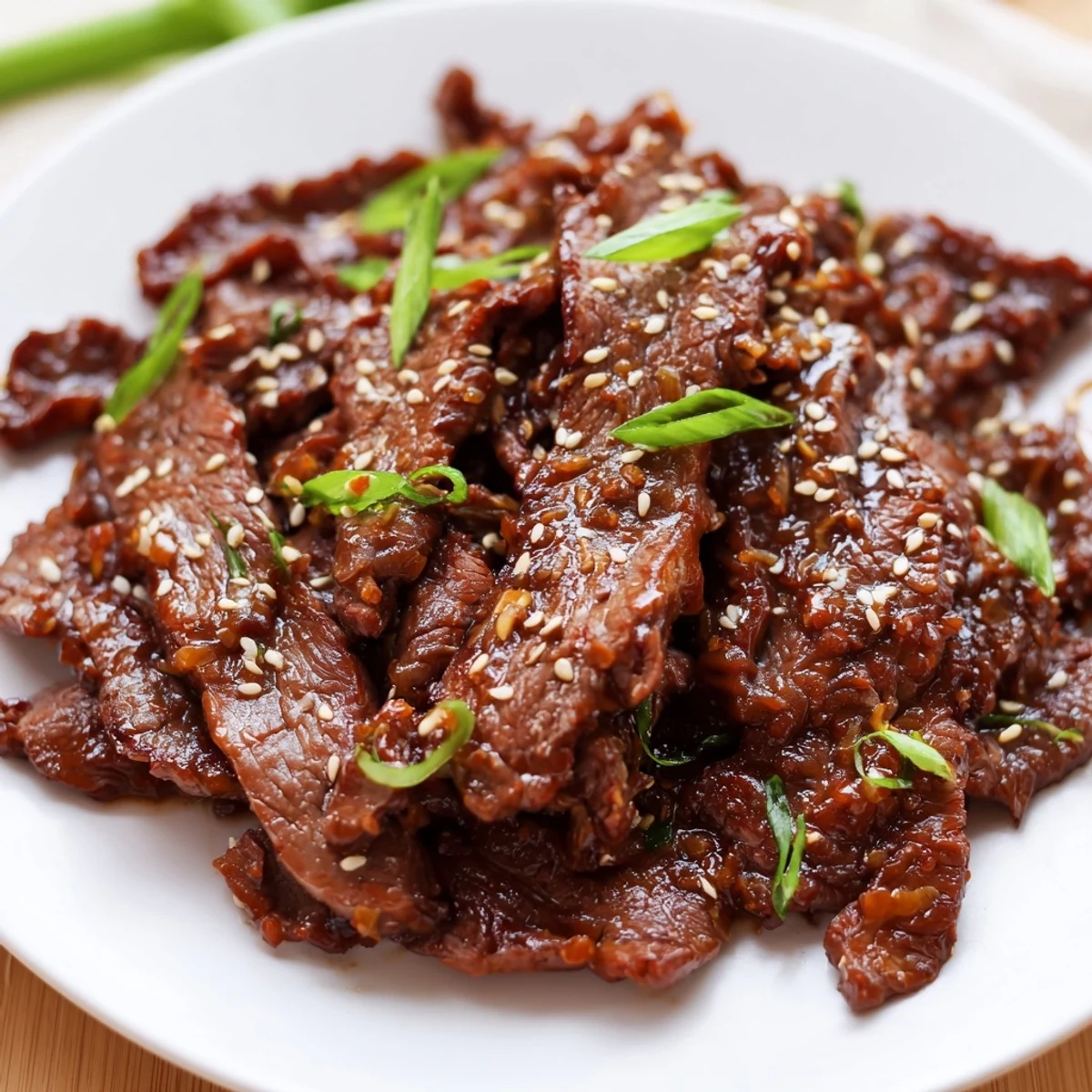 Steaming Ultimate Slow Cooker Mongolian Beef piled on fluffy white rice with green onions and sesame seeds.