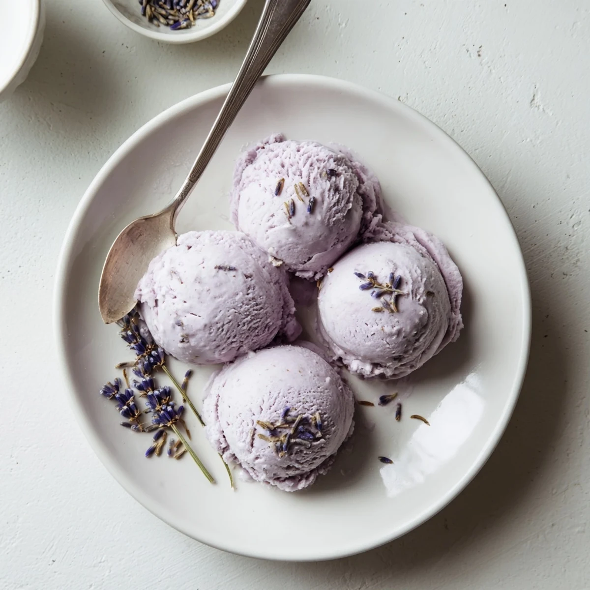A scoop of Lavender Ice Cream melting slightly in a waffle cone on a sunny patio table.