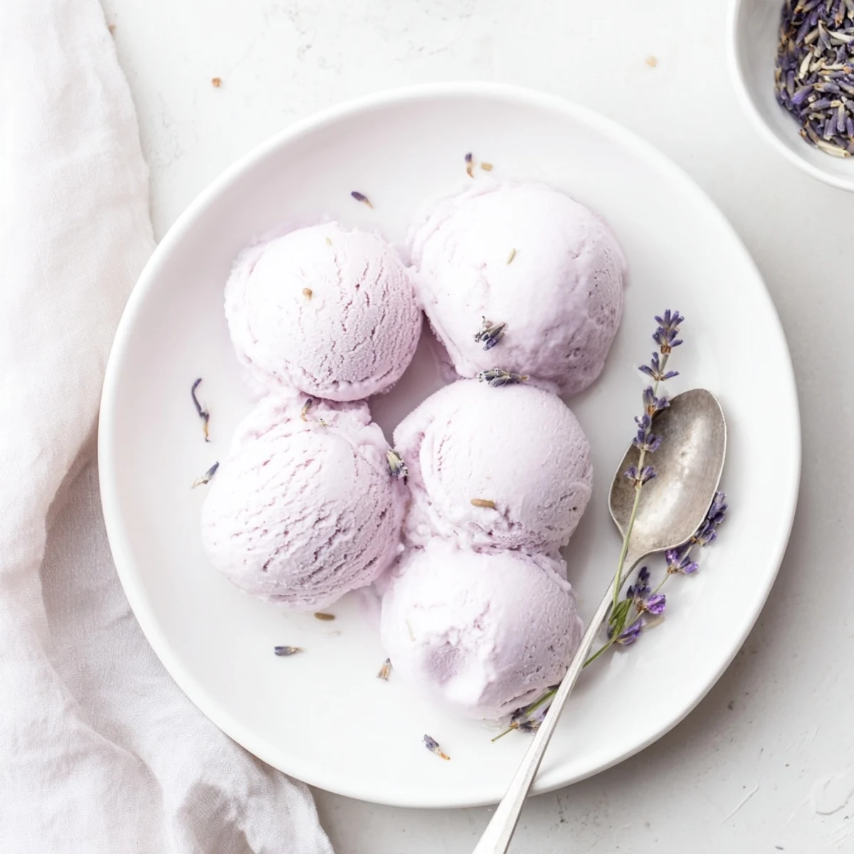 Close-up of Lavender Ice Cream in a glass dish with a drizzle of honey and a lavender garnish.