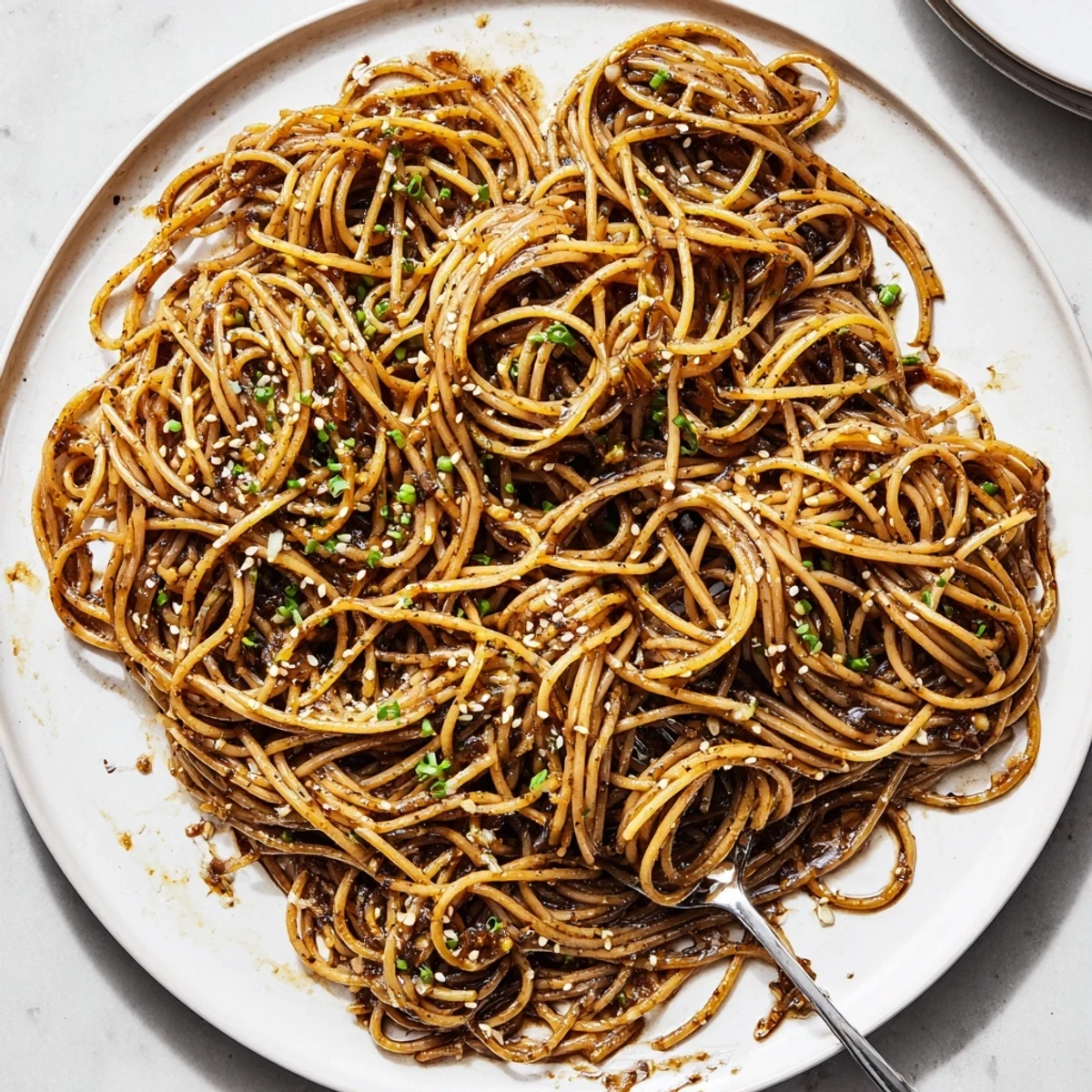 Close-up of Garlic Noodles on a ceramic plate, featuring tender noodles coated in aromatic garlic sauce with a side of iced tea.