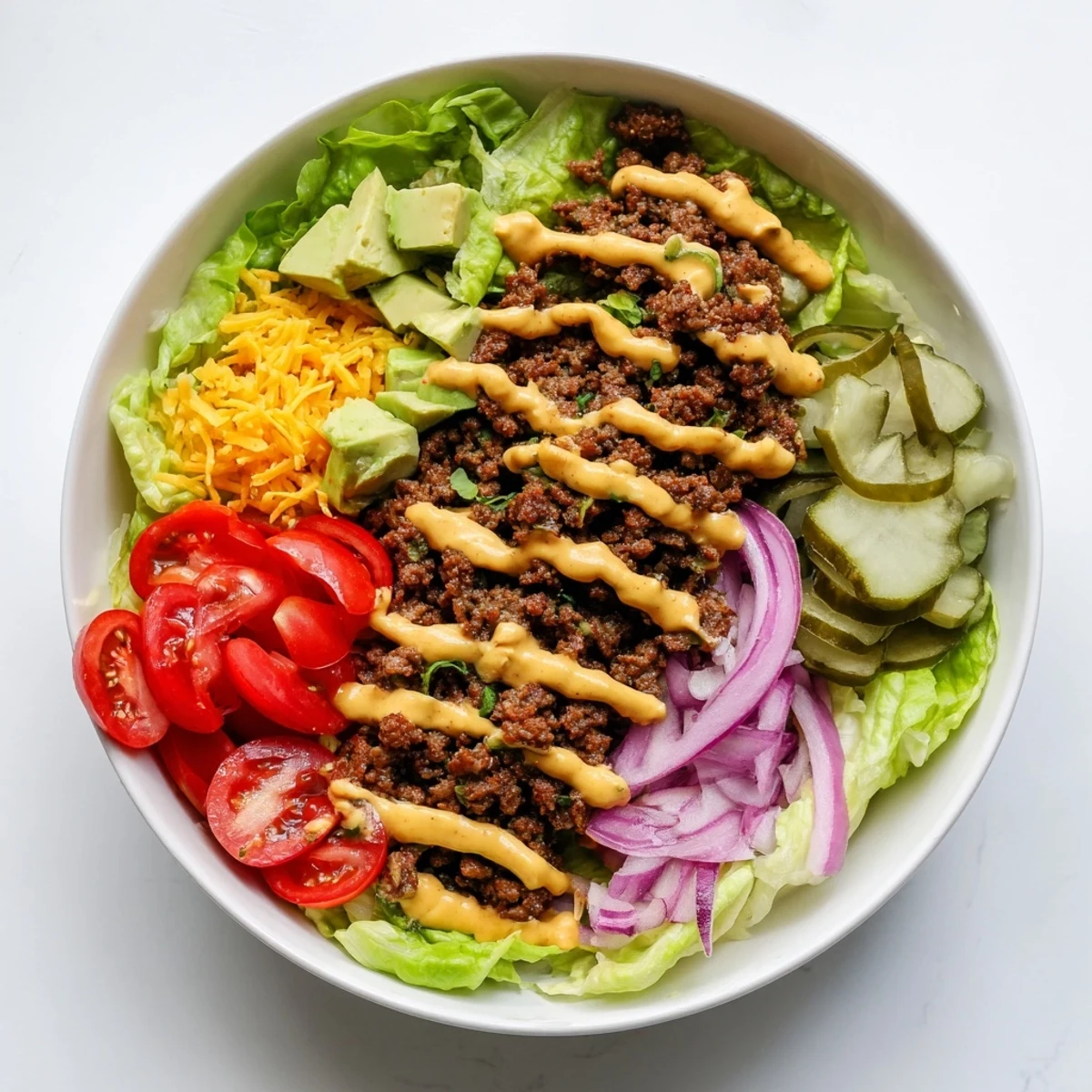 Freshly prepared Burger Bowls with juicy ground beef, cherry tomatoes, and pickles drizzled with creamy burger sauce.