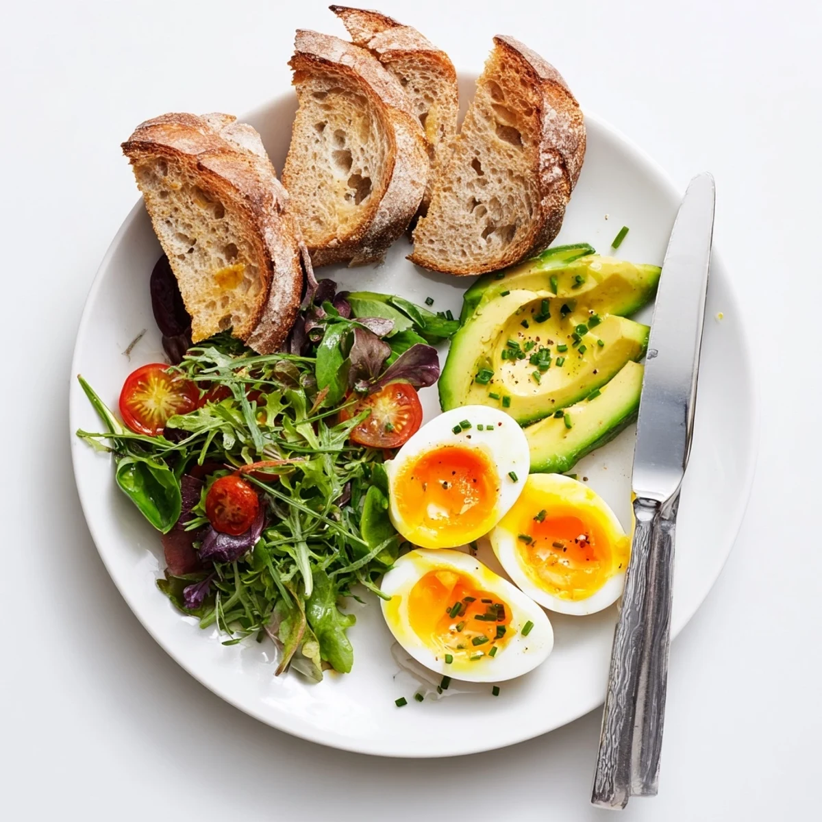 Freshly halved soft-boiled eggs dripping with golden yolks, resting on crisp sourdough toast atop a bed of arugula and cherry tomatoes in this Savory Breakfast Plate.