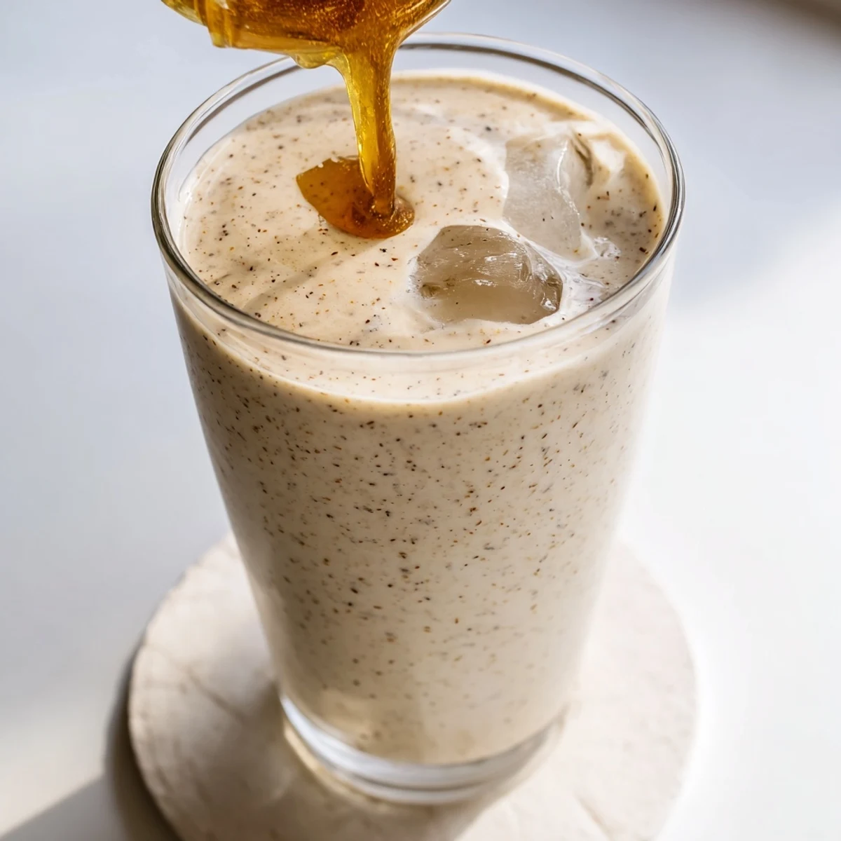 Creamy Greek yogurt banana smoothie poured into a glass with fresh banana slices on top