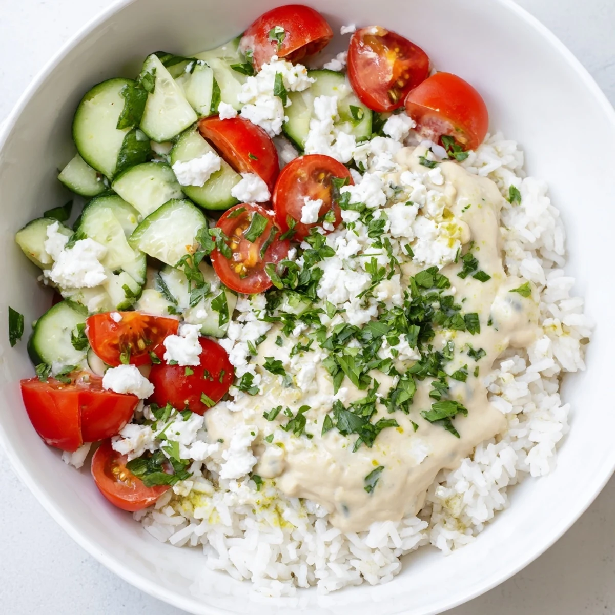 Colorful vegetarian Mediterranean rice bowl topped with hummus and fresh vegetables