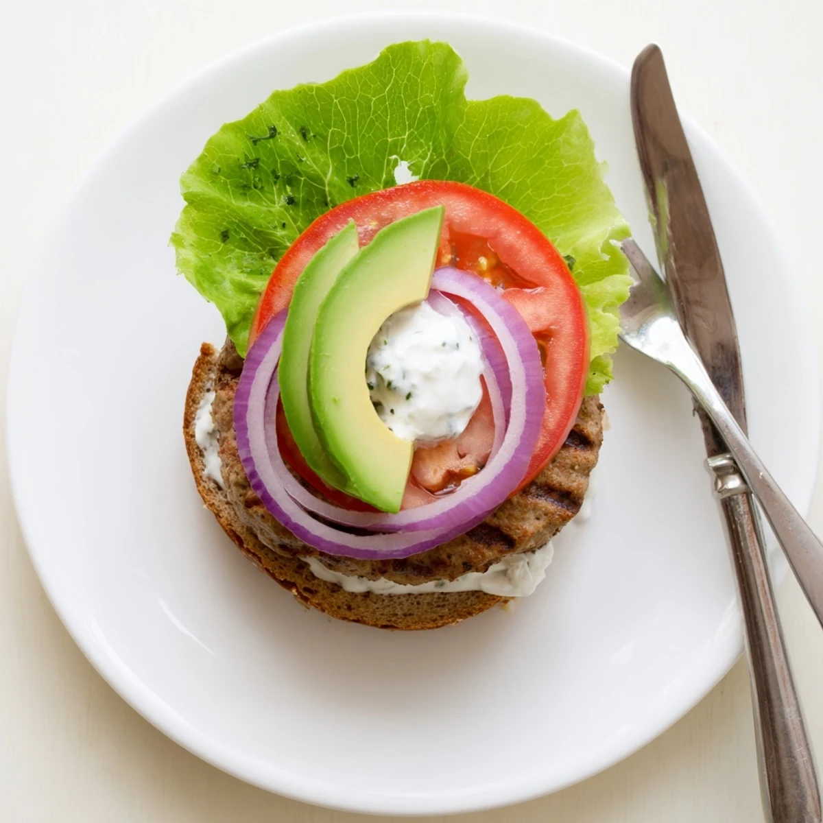 Golden brown turkey healthy high protein burger stacked with fresh lettuce, tomato, and creamy Greek yogurt sauce on a toasted whole wheat bun