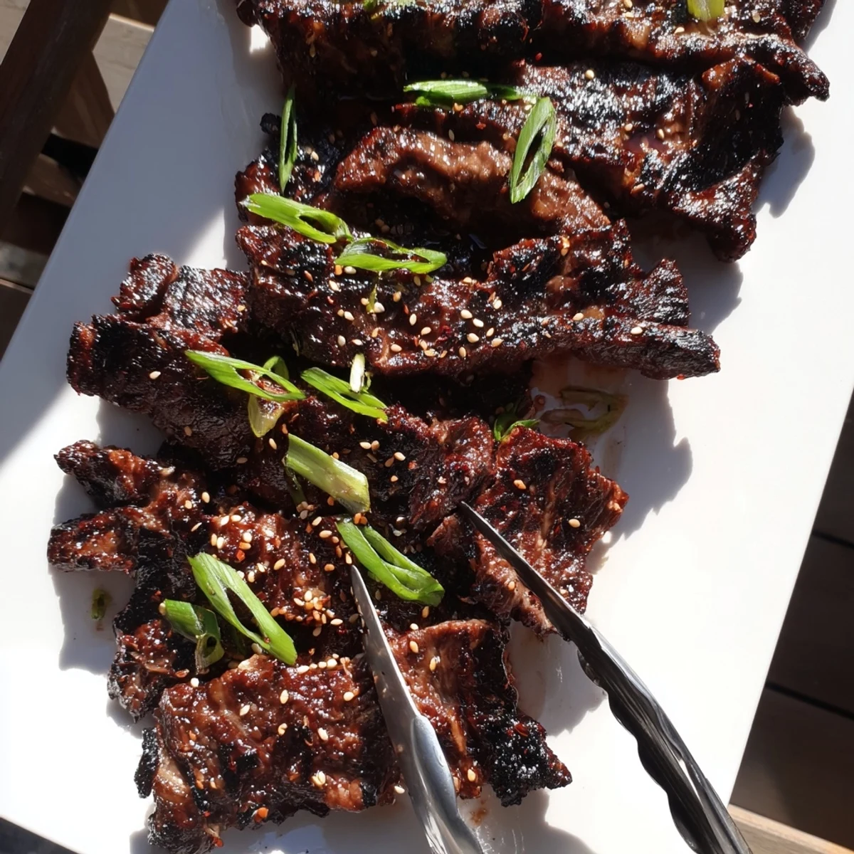 Sizzling Korean galbi grilled ribs displaying caramelized char marks and sesame seed garnish on a white serving platter
