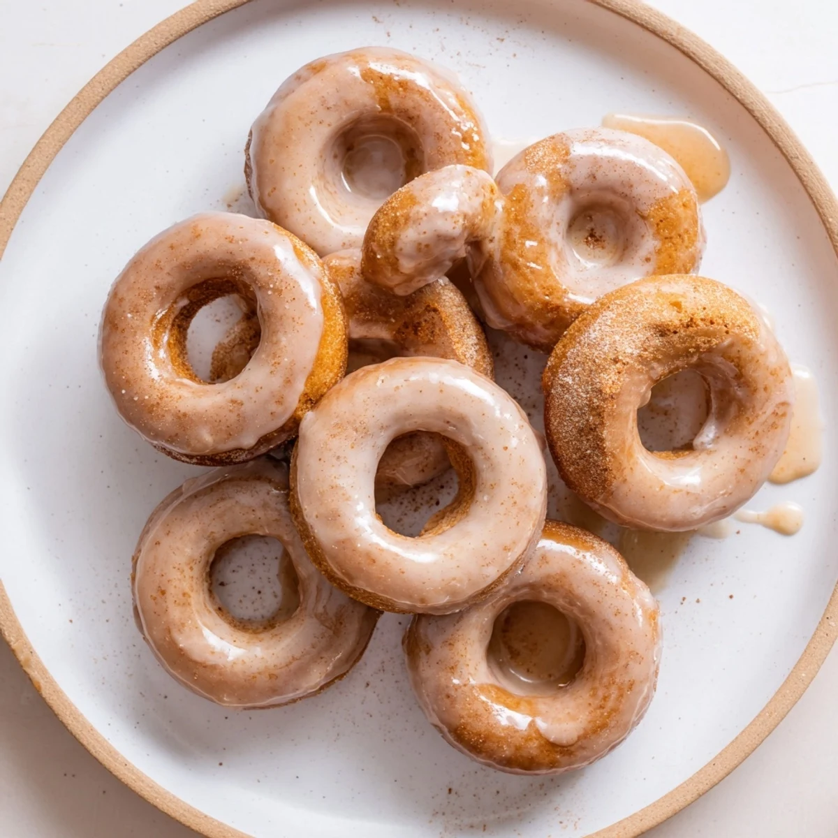 Chewy gluten-free pumpkin mochi donuts drizzled with maple syrup glaze on a wire cooling rack