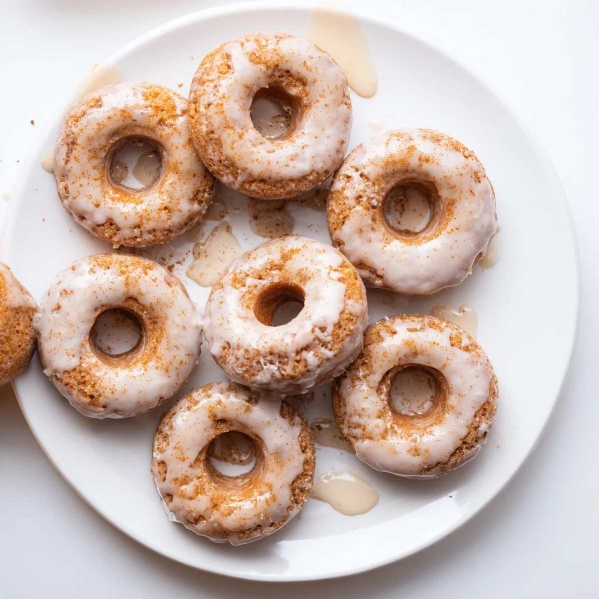 Soft baked pumpkin mochi donuts with luscious maple glaze and nutmeg on white plate