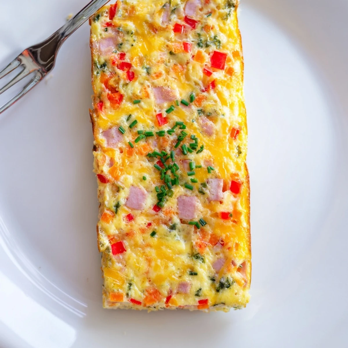 Golden vegetable and ham slice featuring colorful diced vegetables and melted cheddar cheese