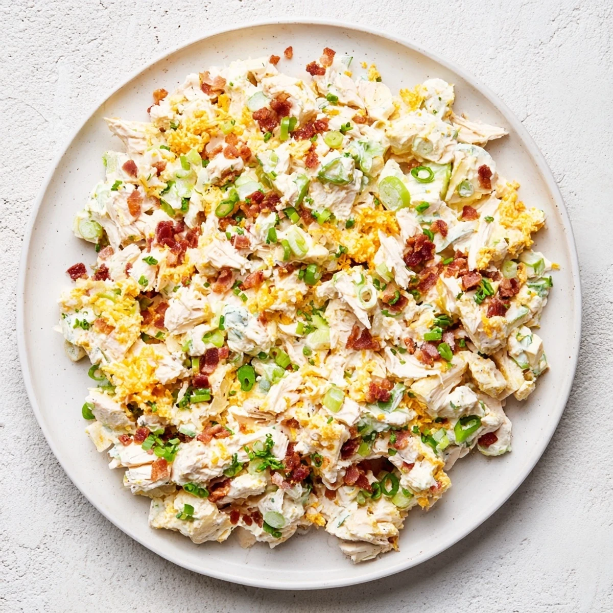 Bowl of high-protein low carb jalapeno popper cottage cheese chicken salad garnished with green onions, cheddar, and smoky paprika