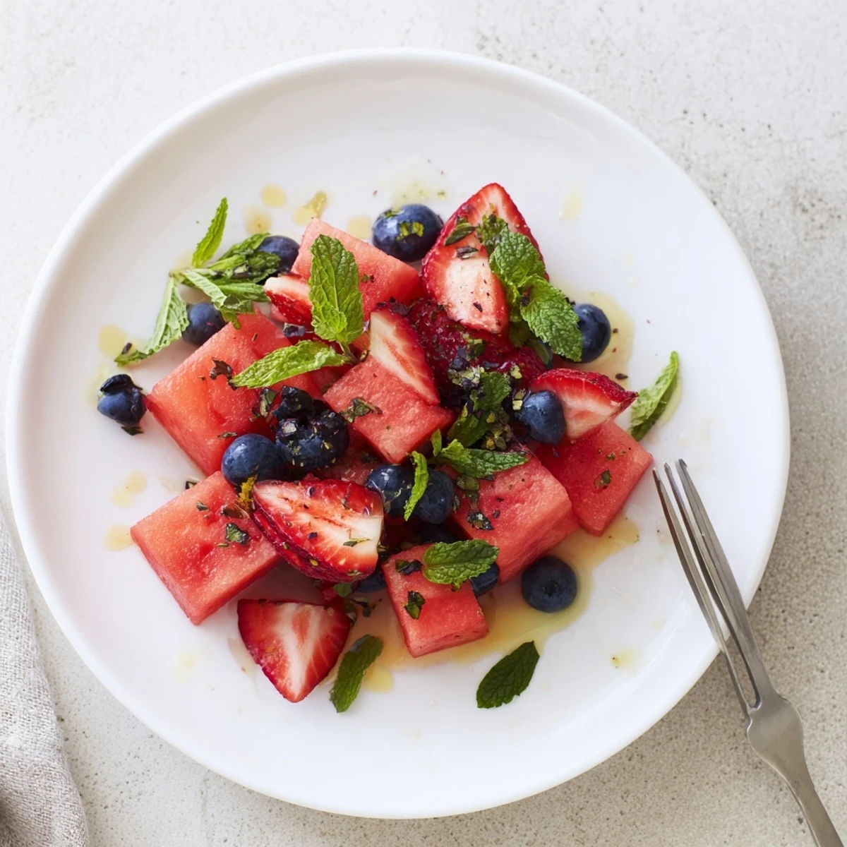 Colorful bowl of juicy watermelon and sweet strawberries tossed in tangy honey lime dressing