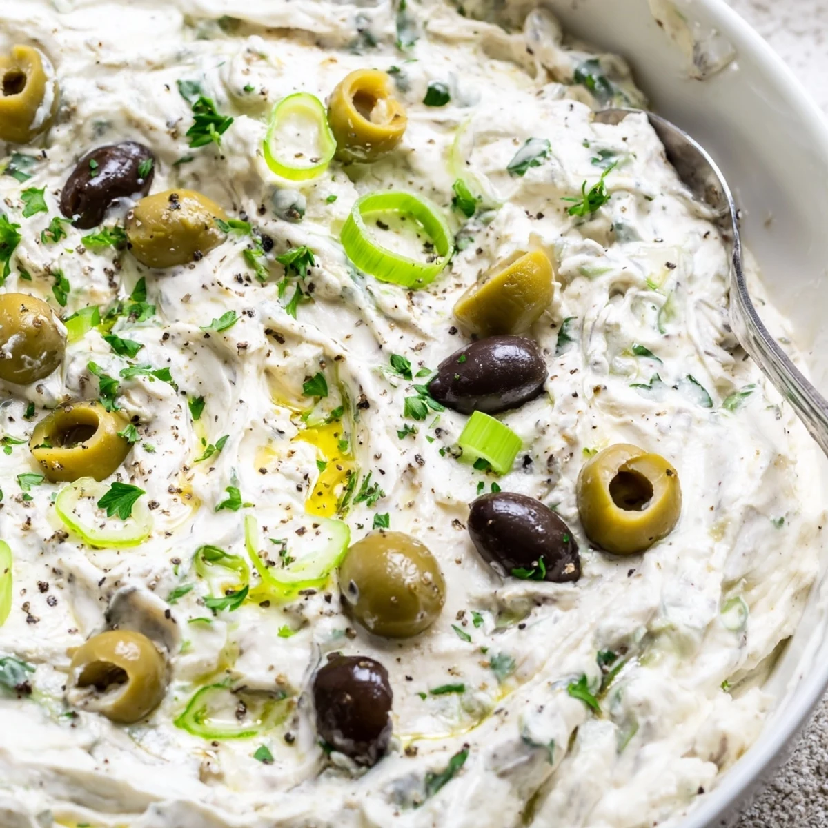 Creamy white cream cheese olive dip topped with chopped green and black olives, served with crispy crackers and fresh vegetable sticks