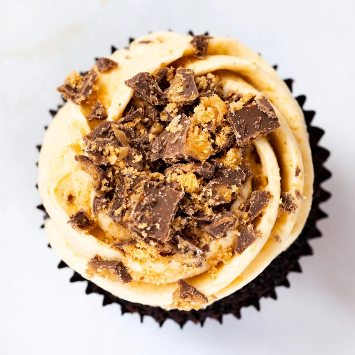 Rich chocolate cupcakes topped with creamy Butterfinger frosting and scattered candy bar pieces.
