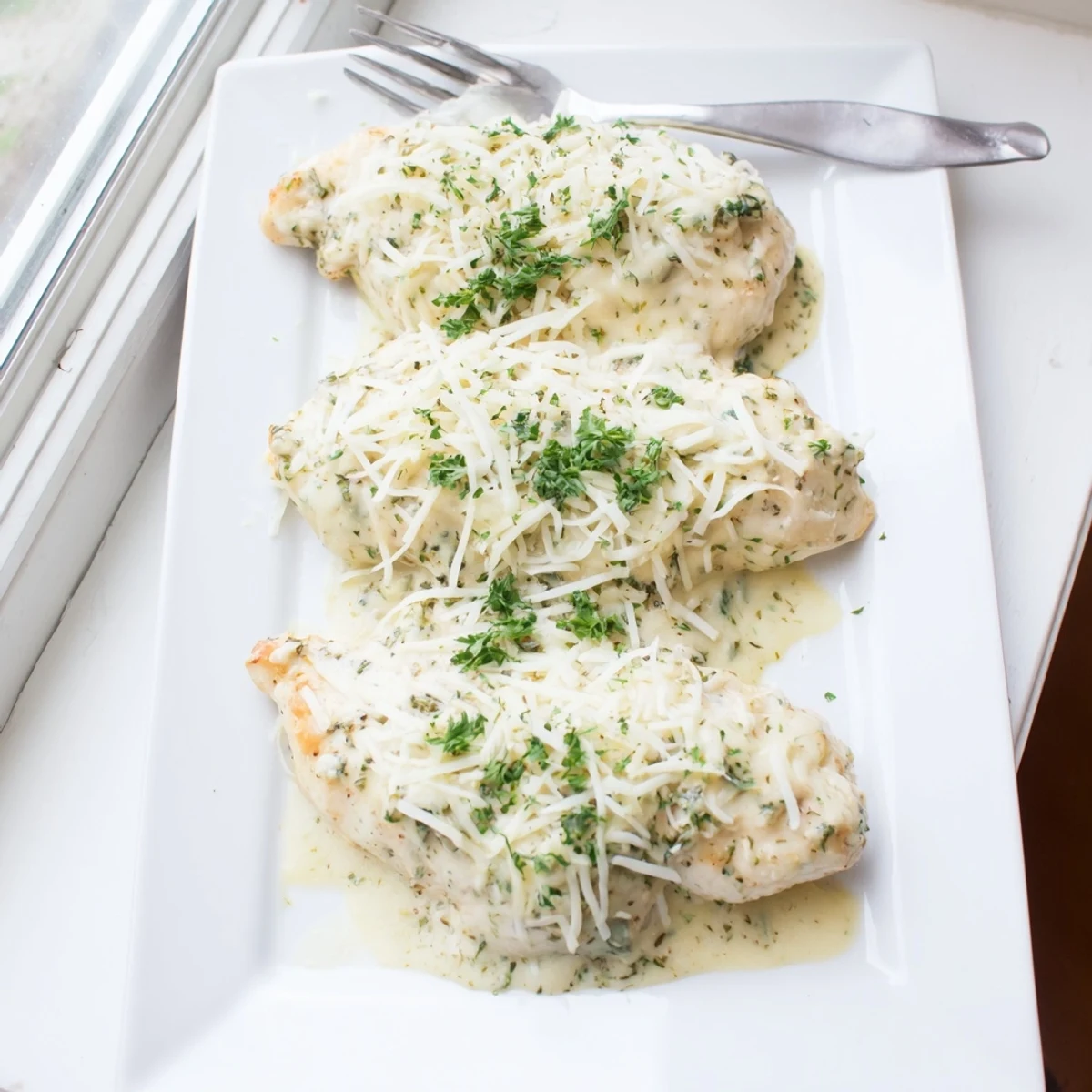 Golden baked parmesan Caesar chicken topped with melted mozzarella and fresh parsley