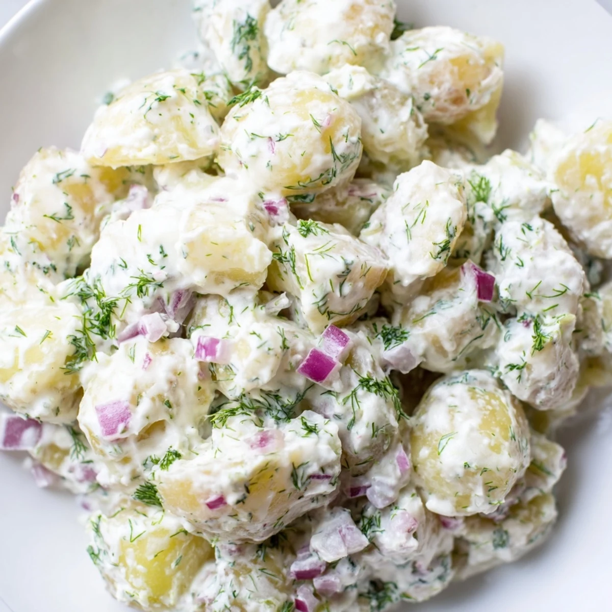 Light and tangy Greek yogurt potato salad with chopped herbs and diced colorful vegetables