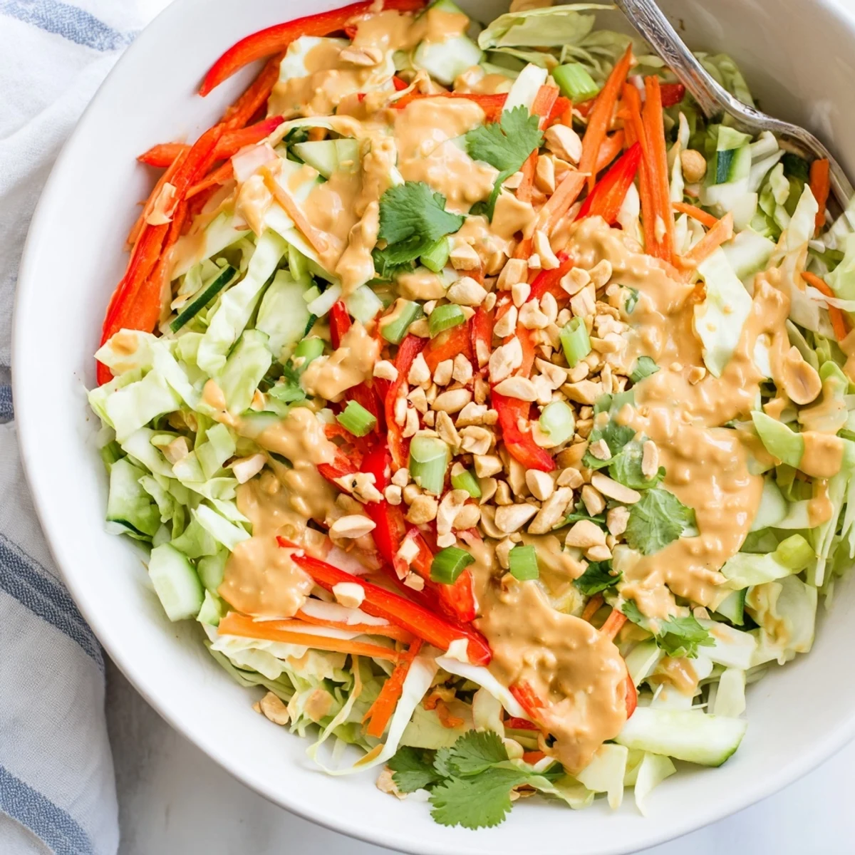 Colorful simple Thai salad peanut sauce featuring crisp vegetables drizzled with creamy peanut dressing and chopped peanuts