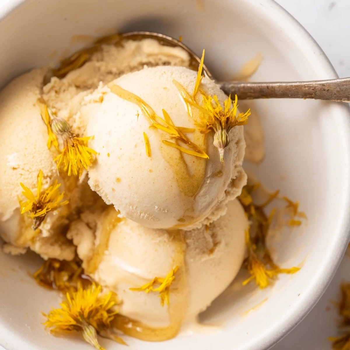 Golden dandelion honey ice cream served in vintage glass with floral garnish