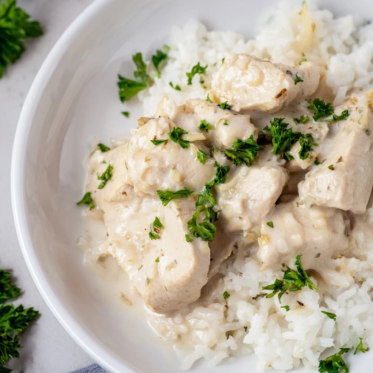 Savory chicken dinner featuring tender rice and spinach in a creamy white sauce garnished with fresh parsley