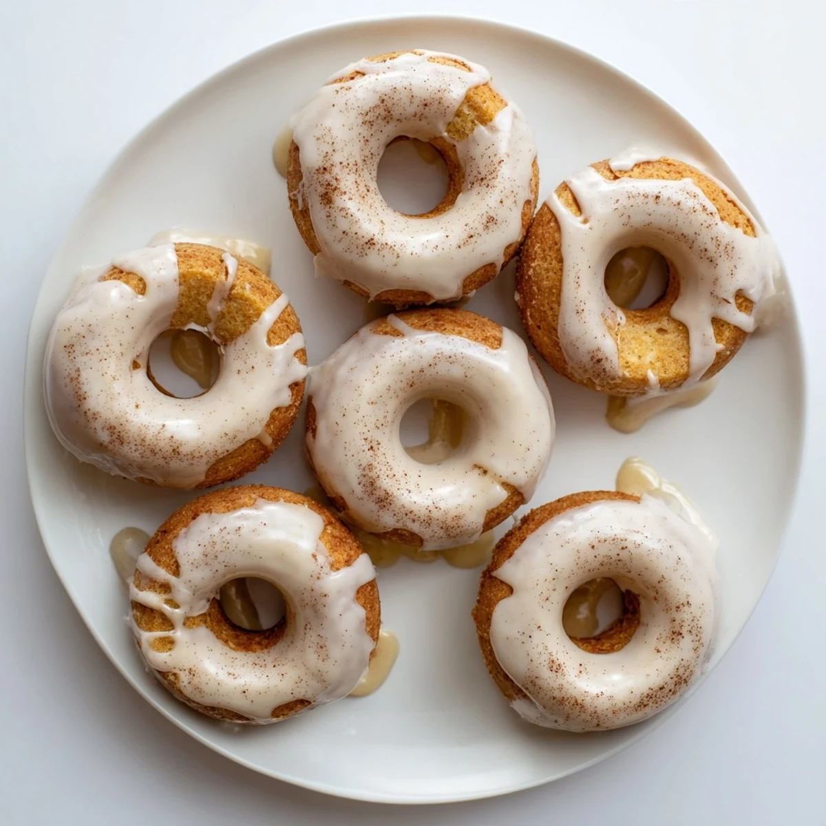 Golden Greek yogurt cake donuts topped with vanilla glaze on a wire rack