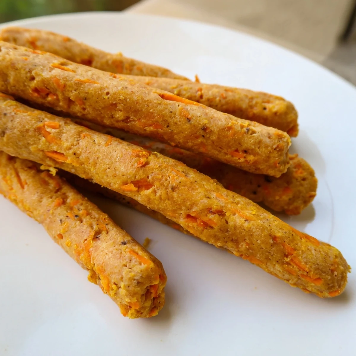 Golden homemade apple and carrot dog chew sticks arranged on parchment paper for crunchy homemade dog treats