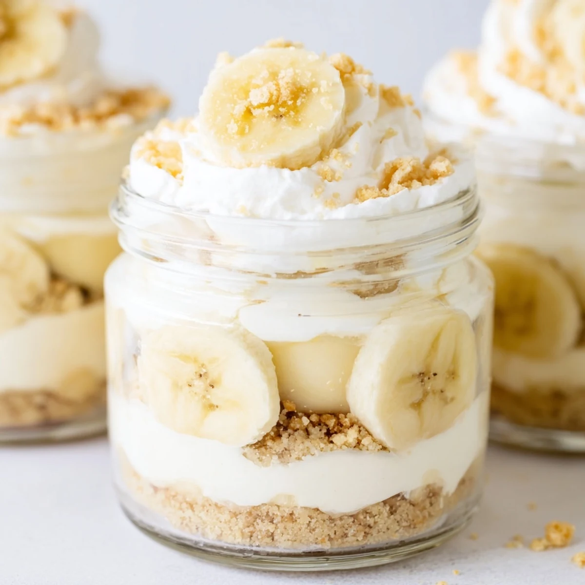 Creamy no bake banana pudding cheesecake cups layered with vanilla wafer crumbs and fresh banana slices