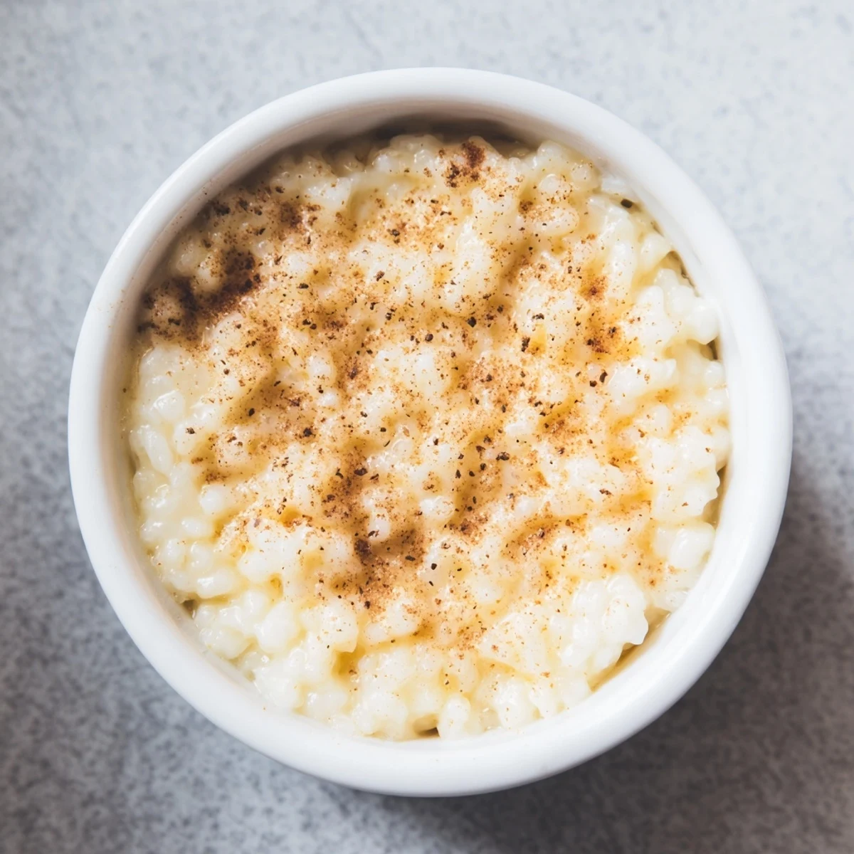 Silky Portuguese rice custard with speckled cinnamon dusting served in small dessert bowls