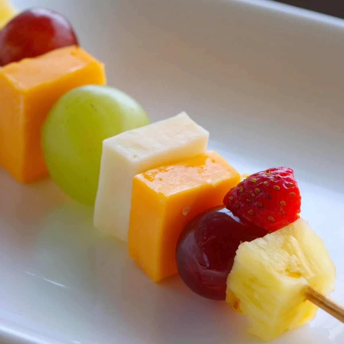 Fresh fruit and cheese kabobs featuring alternating red grapes pineapple chunks and creamy Monterey Jack squares