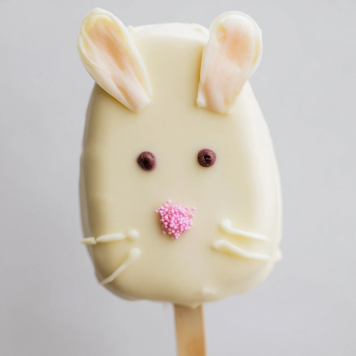 Adorable white chocolate bunny cakesicles with candy eyes and pink ears on sticks