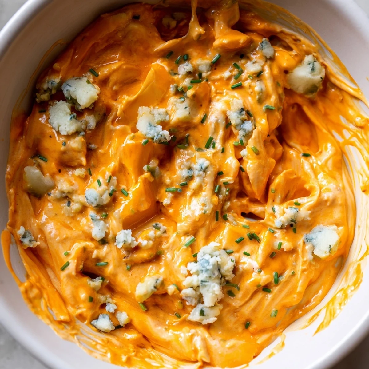 Tangy buffalo pickle dip topped with chopped chives and pickle slices ready for party snacking