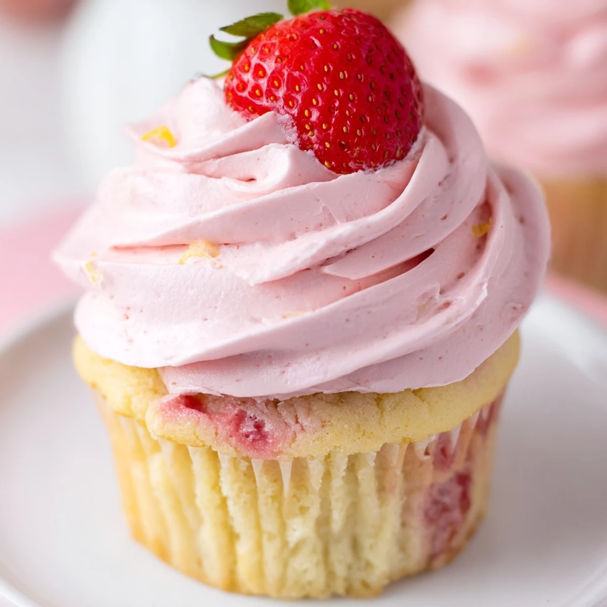 Moist strawberry lemonade cupcakes topped with tangy lemon frosting and fresh berry garnish