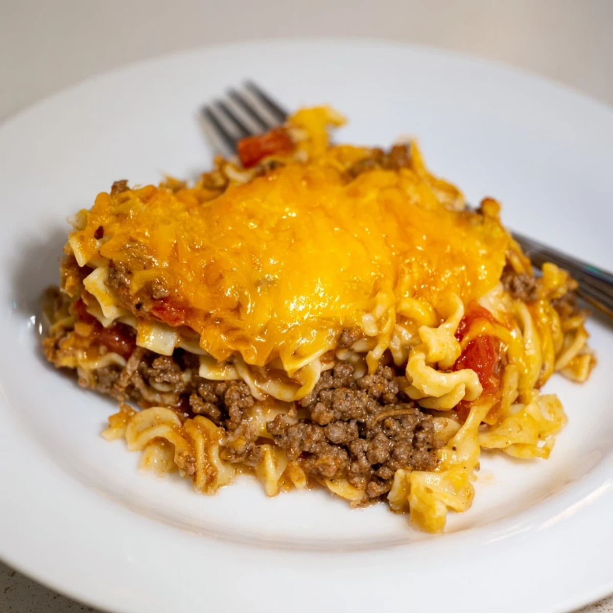 Sliced Beef Lombardi Casserole reveals noodles, tomato sauce, and bubbling cheese
