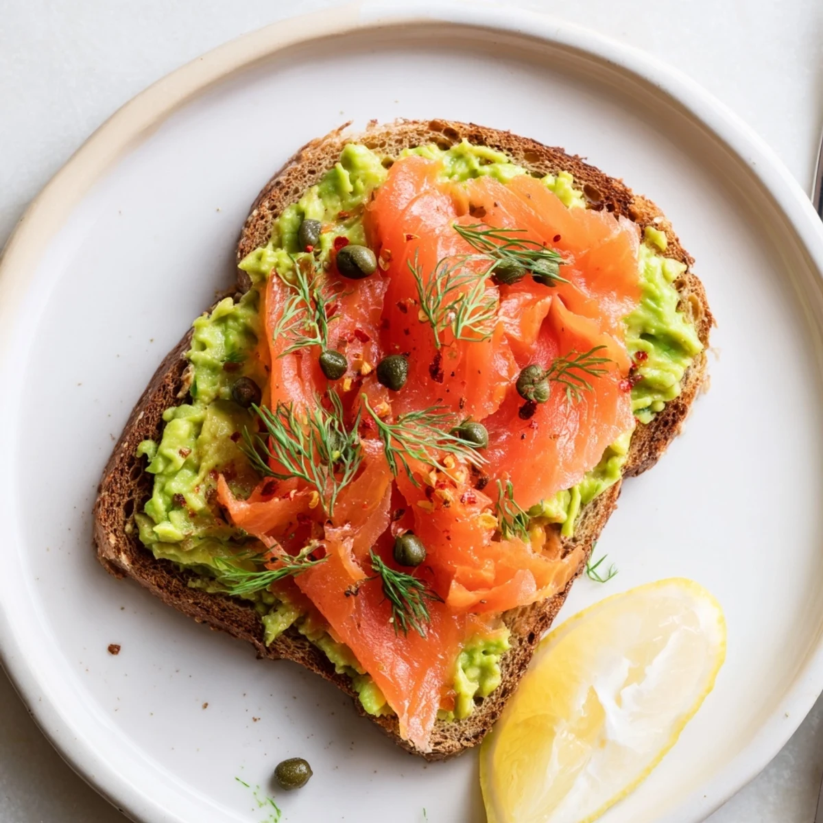 Open faced Salmon Avocado Toast served warm on sourdough with bright lemon