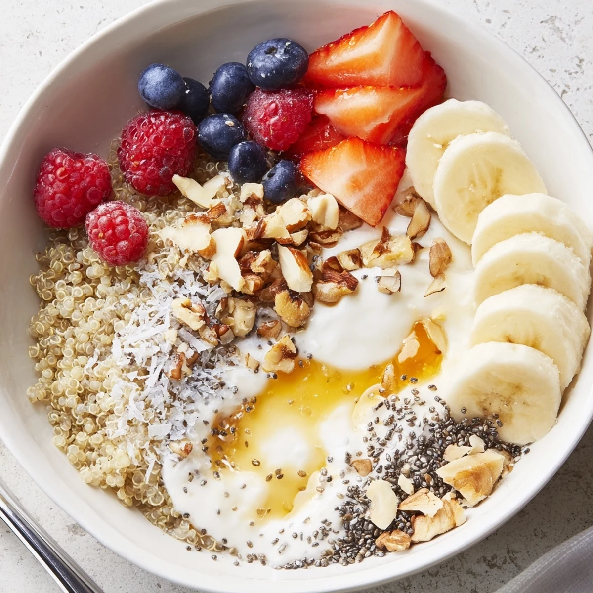 Quinoa Breakfast Bowl with fluffy quinoa, glossy berries, sliced banana, nutty crunch.