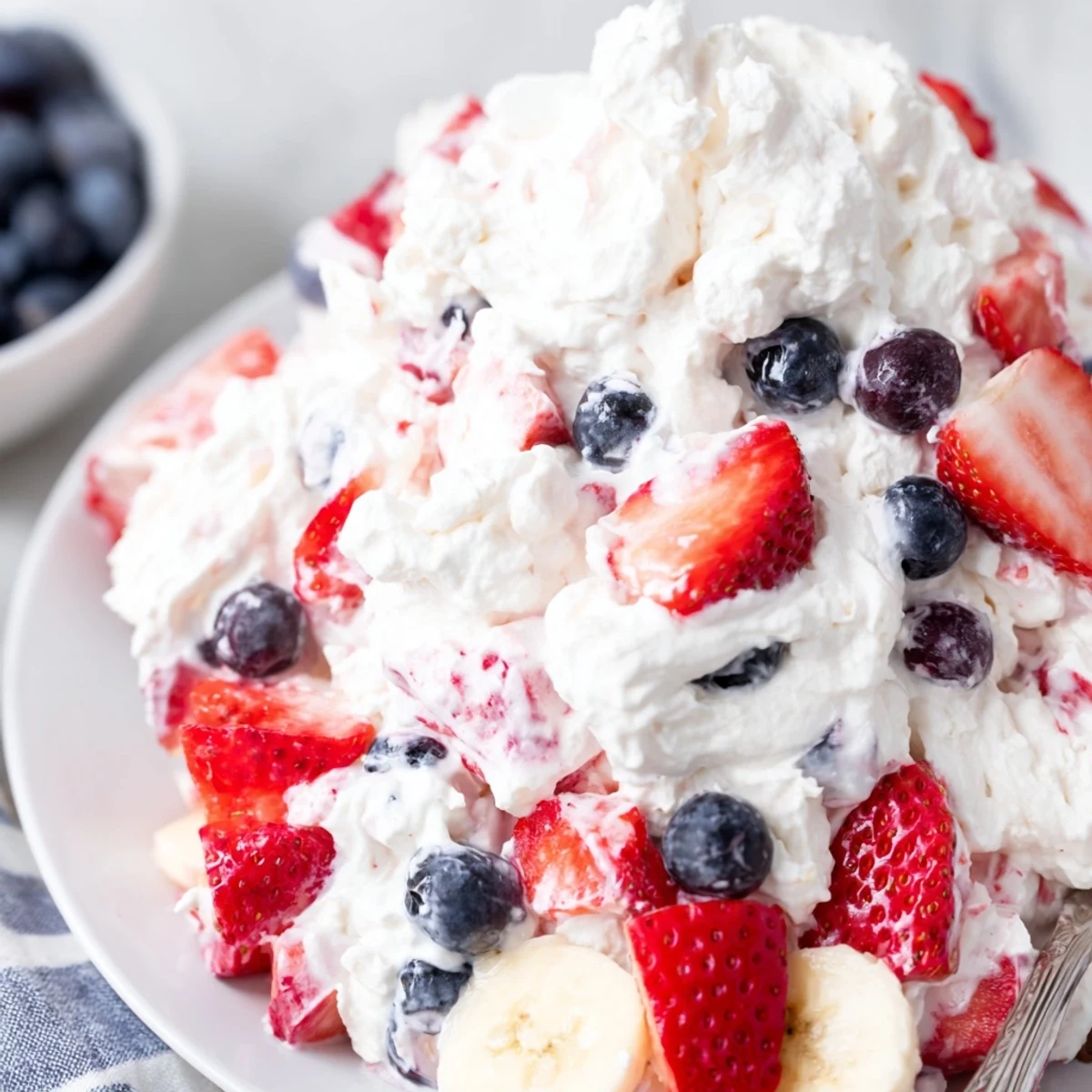 Bright Red White And Blue Cheesecake Salad topped with sliced bananas and extra berries
