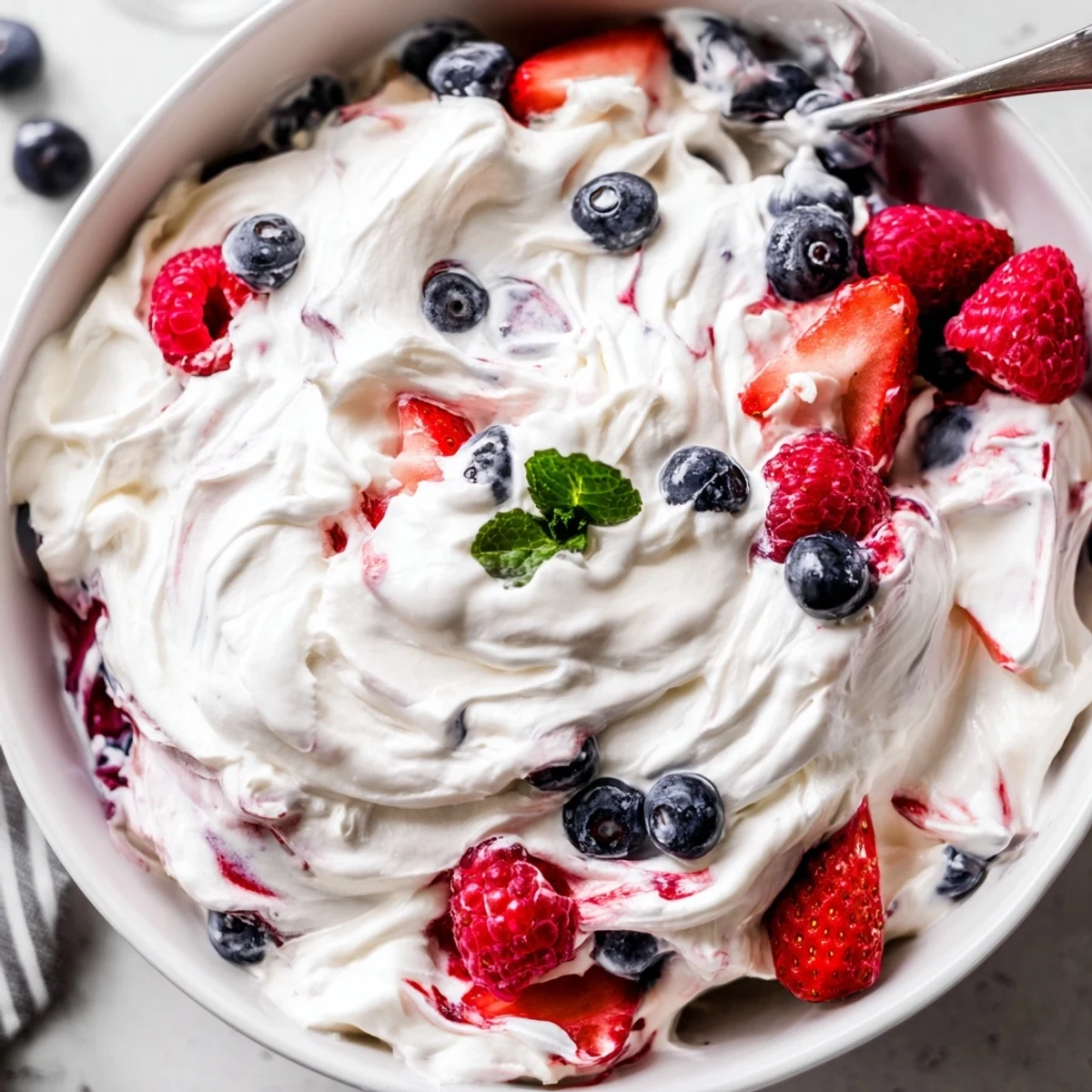 Chilled Red White Blue Cheesecake Salad topped with mint, perfect for picnics